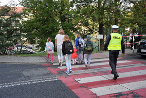 policjant przeprowadzający przez pasy grupke dzieci