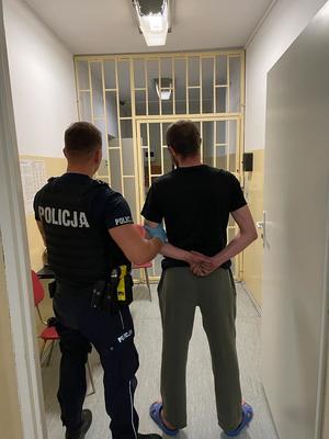 policjant prowadzący nietrzeźwego kierującego do pomieszczeń dla osób zatrzymanych