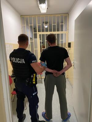 policjant prowadzący nietrzeźwego kierującego do pomieszczeń dla osób zatrzymanych