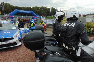 Policjanci na motocyklach i w radiowozie oczekują na start wyścigu rowerowego