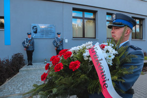 Tablica  Ludwika Drożańskiego, na pierwszym planie policjant z kwiatami