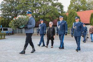 Delegacja, z komendantem wojewódzkim na czele, podchodzi z kwiatami do pomnika katyńskiego