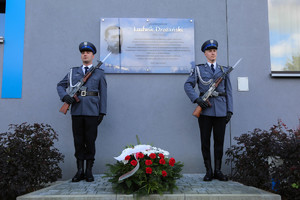 Tablica Ludwika Drożańskiego po bokach stoją policjanci kompanii honorowej ze złożonymi kwiatami