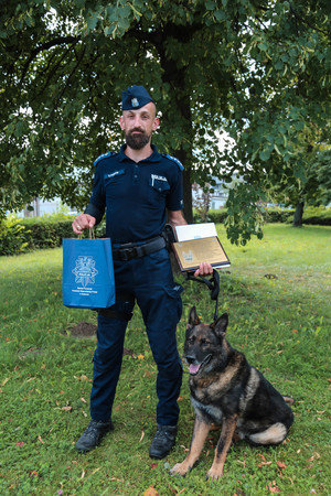 Policjant z psem pozuje z dyplomem