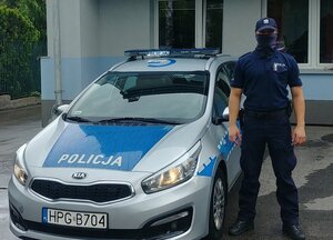 policjant pozuje przed radiowozem