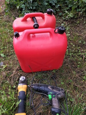 dwa czerwone kanistry z paliwem oraz elektronarzędzia