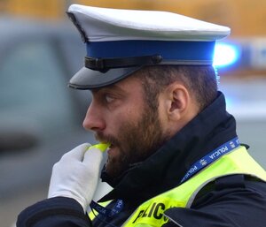 Policjant ruchu drogowego w trakcie regulacji ruchem z gwizdkiem