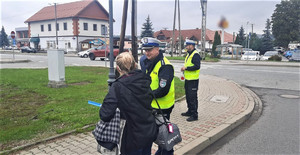policjanci ruchu drogowego wręczają kobiecie element edblaskowy