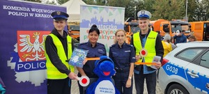 policjantki na pamiątkowej fotografii z uczestnikami ubranymi w kamizelki i czapki policyjne