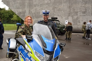 uczennica klasy mundurowej jednej z krakowskich szkół przed budynkiem muzeum siedzi na policyjnym motocyklu obok stoi policjant z drogówki