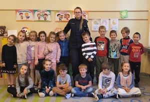 uczniowie na wspólnym zdjęciu z policjantką w szkolnej klasie