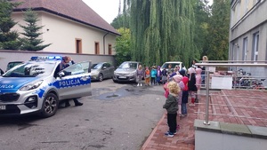 dzieci przed budynkiem oglądają policyjny radiowóz