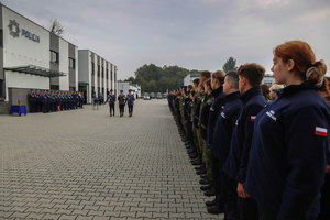 plac apelowy, policjanci idą ze złożoną falgą z prawej uczniowi szkół mundurowych w szeregach