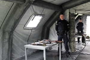 policjant prezentuje broń długą pod namiotem