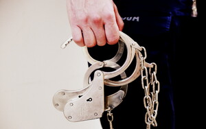 policjant trzyma w ręce kajdanki