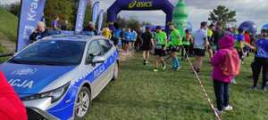 radiowóz stojący nieopodal mety zawodów wsród uczestników biegu