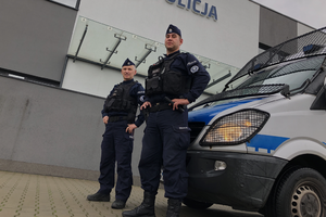 Funkcjonariusze Odziału Prewencji Policji w Krakowie stoją przed radiowozem Mercedes-Sprinter. W tle jednostka policji