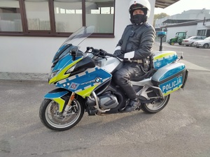 policjant na nowym motocyklu służbowym przed budynkiem. po prawej stronie zdjęcia inne pojazdy