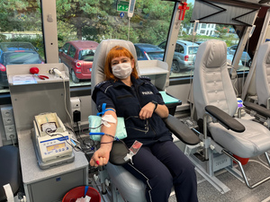 policjantka siedząca na fotelu w mobilnym punkcie poboru w trakcie oddawania krwi