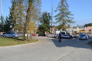 na parkingu przy budynku oddziału szpitalnego stoi umundurowany policjant, obok pojazdy służbowe Policji w Straży Miejskiej