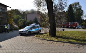 teren przed szpitalem zabezpiecza Policja, w tle zaparkowane radiowozy i wozy strażackie