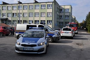 pojazdy służb zaparkowane przed budynkiem szkoły