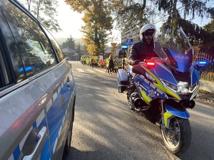 radiowóz i policjant na motocyklu eskortują przemarsz dzieci