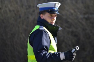 Policjant ruchu drogowego podczas trzymający w ręku elektroniczne urządzenie do badania trzeźwości