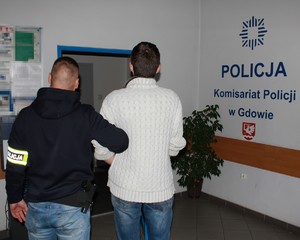 policjant wprowadza zatrzymanego do komisariatu