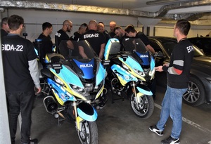 uczestnicy ćwiczeń przyglądają się z bliska motocyklom służbowym ruchu drogowego zaparkowanym w podziemnym garażu komendy