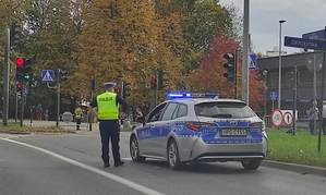 policjant stojący obok radiowozu na jednej z krakowskich ulic