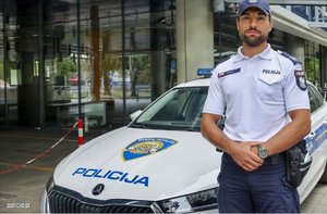 policjant pozujący przed radiowozem - Kamil Styrna