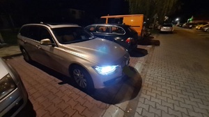 samochód bmw z włączonymi światłami mijania zaparkowany na parkingu