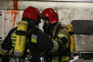 Dwóch strażaków w maskach przeciwgazowych z butlami na plecach