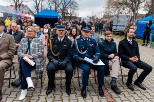 grupa osób m.in. parlamentarzyści, samorządowcy, przedstawiciele służb mundurowych, uczestnicy pikniku siedzący przed trybuną