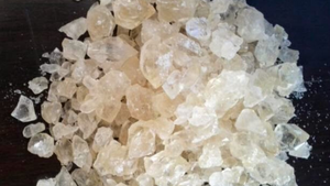 Substancja psychotropowa w postaci białych kryształków rozsypana na czarnym podłożu