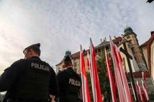 Dwoje policjantów na placu Studzińskiego z widokiem na flagi i Wawel