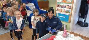 policjantka wykonuje odciski palców chłopcu w mundurku policyjnym