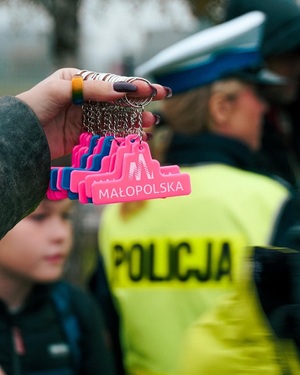 dłoń trzymająca elementy odbladkowe w formie breloczków z napisem Małopolska w tle policjantka drogówki