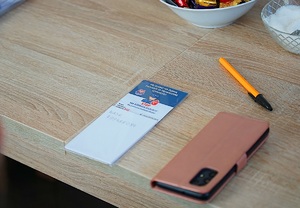 położony na stole długopis, telefon komórkowy a obok magnes z informacją profilaktyczną oraz zapisanym numerem do cert polska