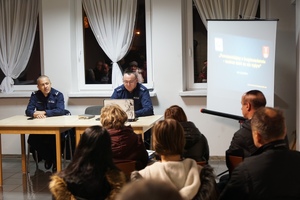 zastępca komendanta wraz z naczelnikiem prewencji siedzący przez mieszkańcami w trakcie debaty społecznej