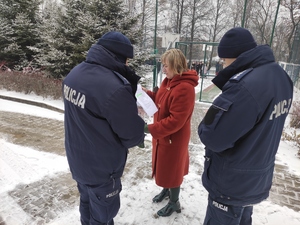 4.	Dyrektor Zespołu Szkół nr 1 w Olkuszu przekazuje policjantom dokument. W tle,  na placu stoi grupa ewakuowanej młodzieży  szkolnej.