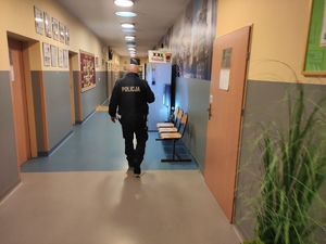 Policjant idzie korytarzem szkolnym w poszukiwaniu niebezpiecznego urządzenia.