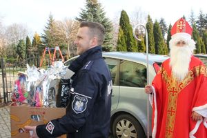 policjant niosący prezenty dla dzieci, obok stoi święty mikołaj