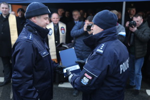 Policjant wręcza drugiemu policjantowi teczkę z dokumentami