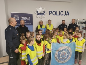 Pierwszaki z Piotrowic odwiedziły policjantów dzieci i policjanci na wspólnym zdjęciu  w tle roll up