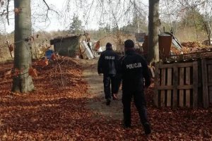 dwóch policjantów sprawdza ogródki działkowe w poszukiwaniu osób bezdomnych