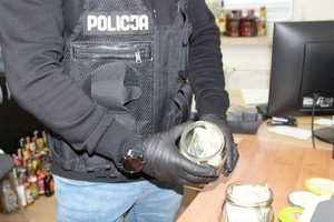 policjant trzymający w rękach słoik z pieniędzmi