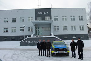 komendant powiatowy policji w Brzesku wraz z przedstawicielami samorządów stojący przy przekazywanym samochodzie