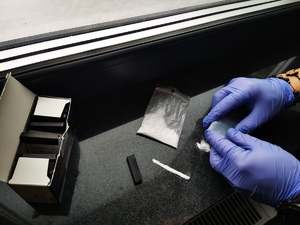 Policjanci badają podręcznym narkotestem biały proszek